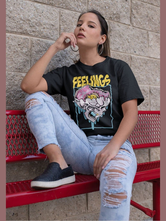 Woman wearing NicholesGifts Women Feelings Skeleton black short sleeve t-shirt with graphic design sitting on red bench against brick wall