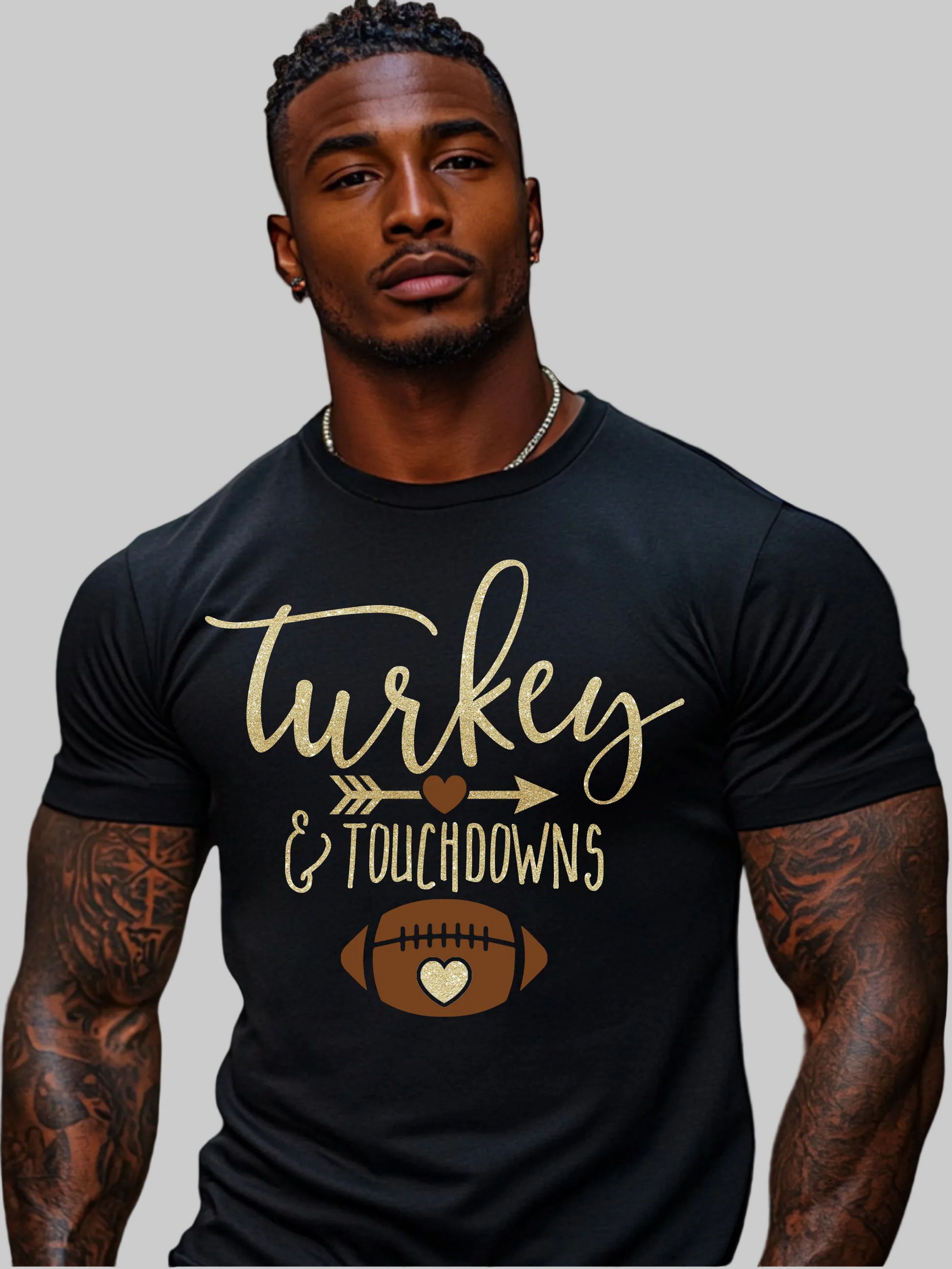 A muscular man with tattoos wearing a black t-shirt with a gold and brown graphic that reads 'Turkey & Touchdowns' with a football design, set against a plain white background - NicholesGifts