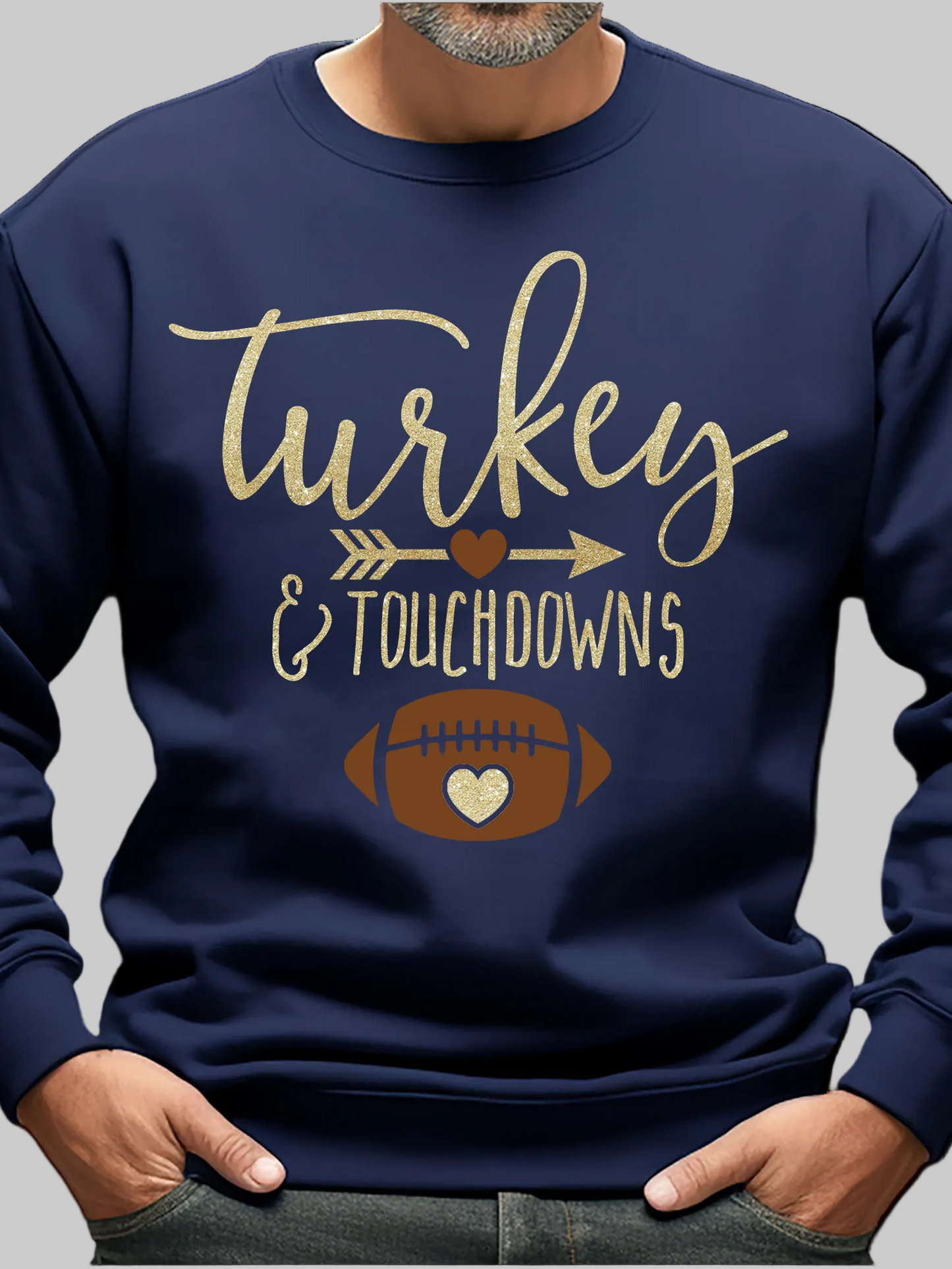A man wearing a navy blue crewneck sweatshirt with a graphic that reads 'Turkey & Touchdowns' in gold lettering, featuring a football with a heart-shaped white center, shown against a plain white background - NicholesGifts